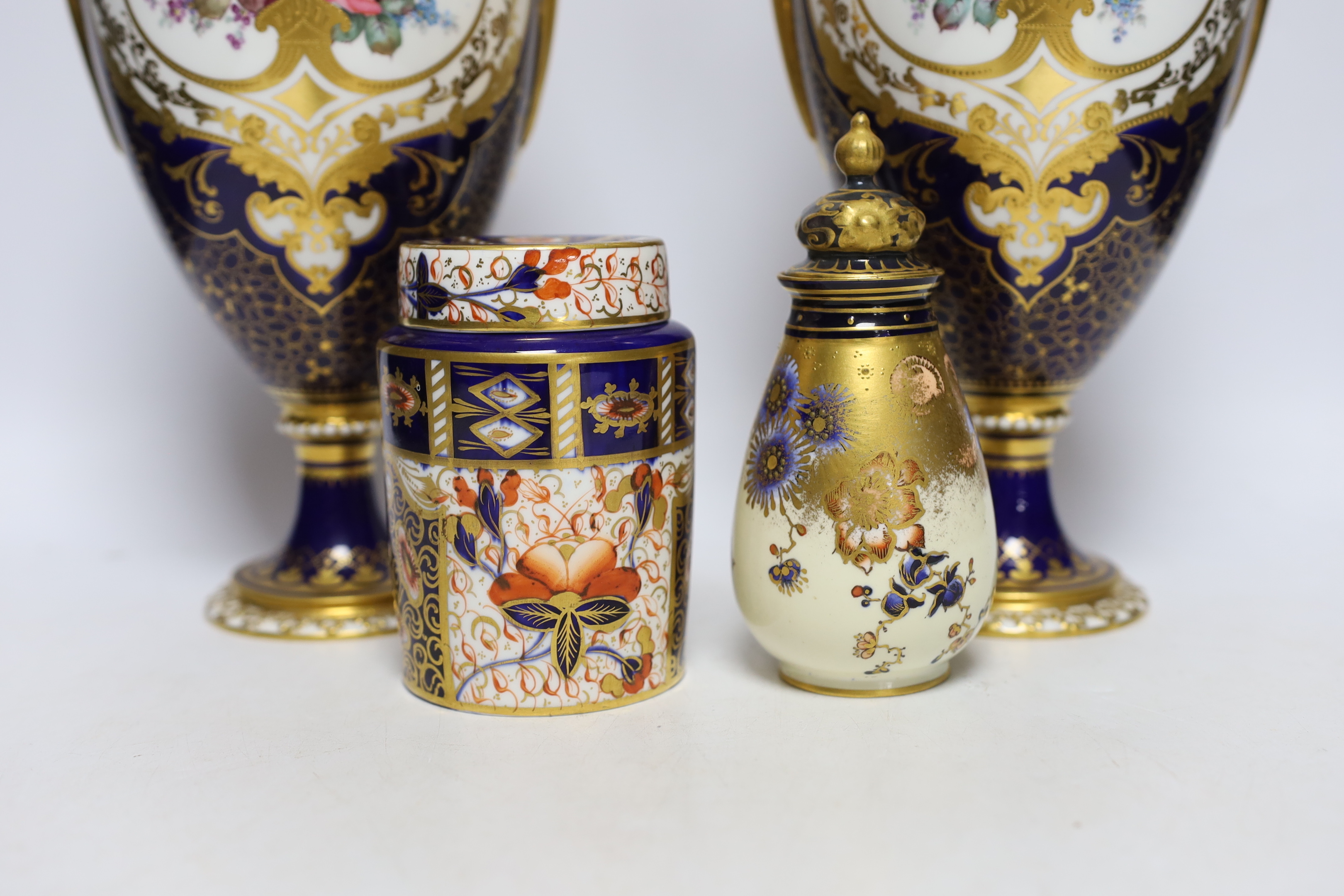 A pair of Royal Crown Derby porcelain urns and covers together with a smaller example and an Imari style jar and cover, 36cm high
